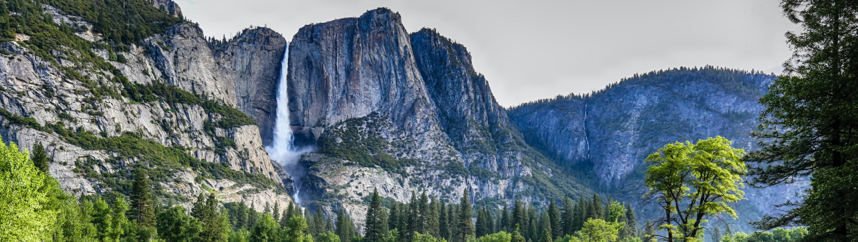 A mountain landscape with a waterfall in the distance coming down off a cliff