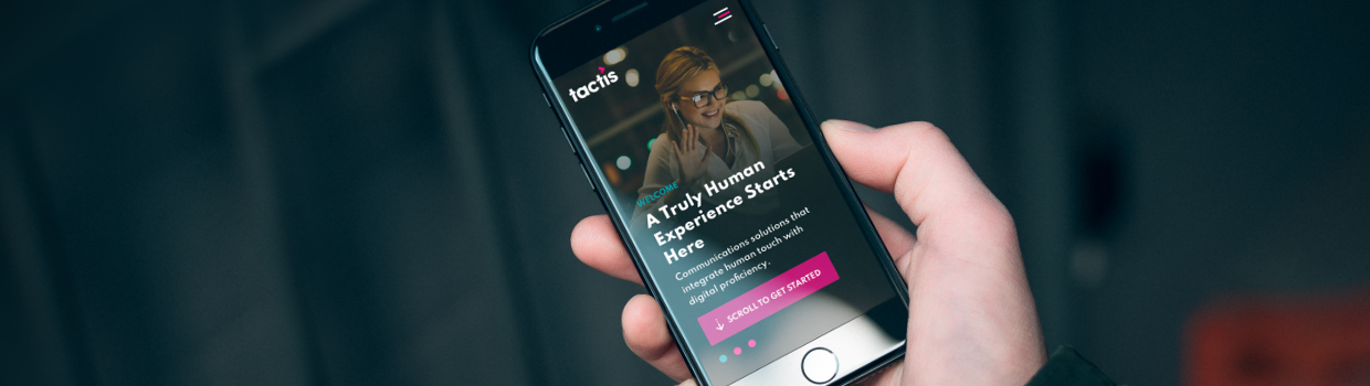 An iPhone being held in a hand showing the Tactis homepage