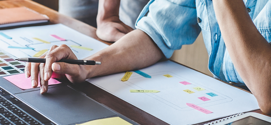 abstract zoomed in view of two employees working on a new website wireframe and color swatches